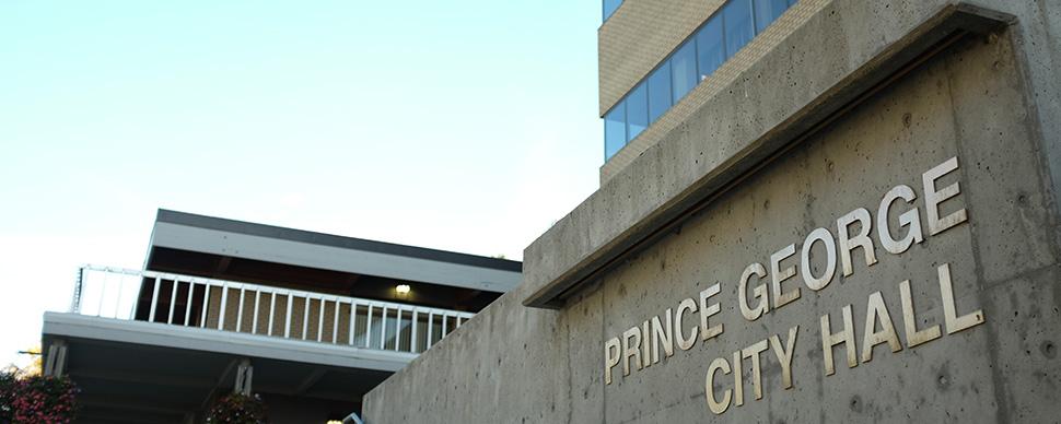 Low angle photograph of City Hall. Metal text on cement wall reads 'PRINCE GEORGE CITY HALL'